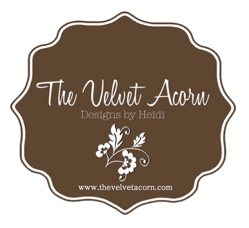 May include: A brown and white logo for "The Velvet Acorn Designs by Heidi." The logo features a decorative floral design and the website address www.thevelvetacorn.com.