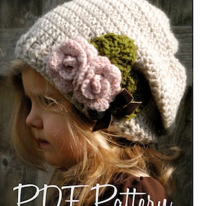 May include: A crocheted hat with a beige base and a green and pink flower embellishment. The hat is worn by a child with blonde hair. The text "PDF Pattern" is visible at the bottom of the image.