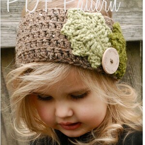 May include: A brown crocheted headband with a green crocheted flower and a wooden button. The headband is worn by a young girl with blonde hair.