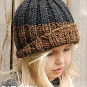 Puede incluir: Un gorro de punto negro y marrón con un patrón de canalé. El gorro tiene un borde doblado y lo lleva puesto un niño con el pelo rubio.
