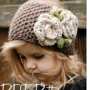 Puede incluir: Una diadema de crochet marrón con dos flores de crochet blancas y hojas verdes. La diadema la lleva puesta una niña pequeña con el pelo rubio. El texto "PDF Pattern" es visible en la parte inferior de la imagen.