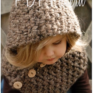 May include: A brown crocheted hooded scarf with wooden buttons. The scarf is being worn by a young child with blonde hair.