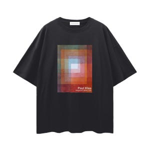 Op de afbeelding: Zwart T-shirt met korte mouwen met een kleurrijk geometrisch ontwerp geïnspireerd op Paul Klee's "Polyphonic White 1930". Het kunstwerk is een vierkante compositie van gelaagde rechthoeken in tinten oranje, rood, blauw en groen. De tekst "Paul Klee Polyphonic White 1930" staat eronder.
