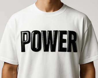 May include: White t-shirt with the word "POWER" in large, glossy black letters across the chest. The shirt has short sleeves and a crew neck. The design is simple and bold.