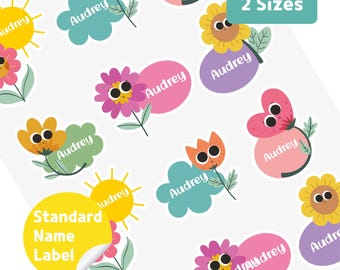 May include: A sheet of colorful name labels with floral and cloud designs. Each label features the name "Audrey" in white text. The labels come in various shapes, including flowers, suns, and clouds. The text "2 Sizes" and "Standard Name Label" are also visible.