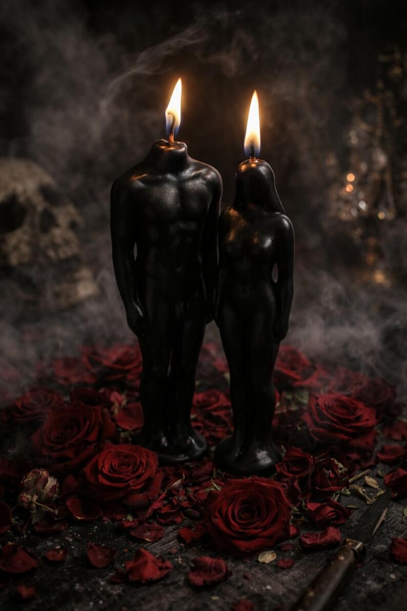 Puede incluir: Dos velas de cera negra con forma de figuras humanas, una con un torso m&aacute;s ancho y otra con una complexi&oacute;n esbelta, ambas de pie con las mechas encendidas. Las velas est&aacute;n rodeadas por numerosas flores de rosa de color rojo intenso.