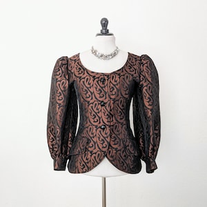 May include: A brown and black patterned blazer with long sleeves and a fitted silhouette. The blazer has a round neckline and a button closure.