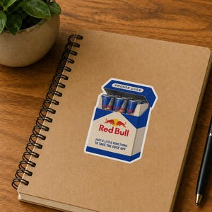May include: A rectangular sticker featuring a blue and white cigarette pack design labelled Fridge Cigs. The pack contains small blue and silver energy drink cans and displays the Red Bull logo with the text Just a little something to take the edge off.