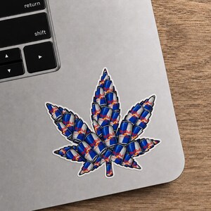May include: A sticker in the shape of a cannabis leaf, composed of stacked Red Bull energy drink cans. The sticker is on a laptop, with a wooden surface in the background. The cans are blue, silver, red, and white.