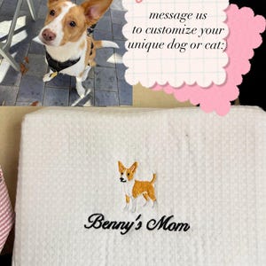K&ouml;nnte beinhalten: Wei&szlig;es Haustierbett mit Waffelstruktur, bestickt mit einem Hundedesign und dem Text "Benny's Mom". Im Hintergrund ist ein Hund mit braun-wei&szlig;em Fell zu sehen. Das Bild enth&auml;lt eine Notiz mit der Aufschrift "Schreiben Sie uns, um Ihren einzigartigen Hund oder Ihre Katze anzupassen:)"