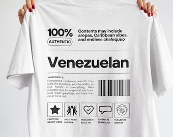 May include: A white t-shirt featuring black text and graphics on the back. The design mimics a nutrition label with the word Venezuelan, a barcode, and icons labeled Certified Beach Vibes, 100% Pana Energy, Resilience Built-in, Fluent in Spanglish, and Fueled by Arepas.