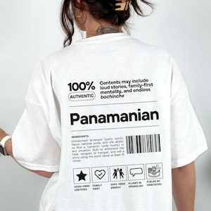 May include: White t-shirt with the word "Panamanian" in a bold black font. The shirt features text and graphics, including "100% Authentic" and a list of "ingredients" with icons. The overall design is casual and modern.