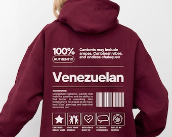 May include: A maroon hoodie with the word "Venezuelan" in white block letters. The back of the hoodie features text including "100% Authentic" and a list of ingredients. The hoodie has a hood and long sleeves.