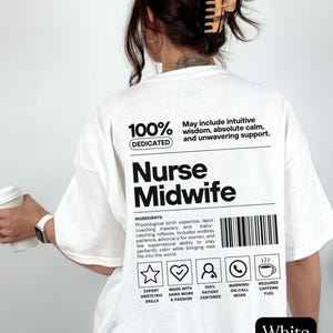 May include: A white t-shirt featuring black text on the back that reads Nurse Midwife, along with a list of ingredients including physiological birth expertise, labour coaching mastery, and baby-catching reflexes, plus five icons and a barcode.