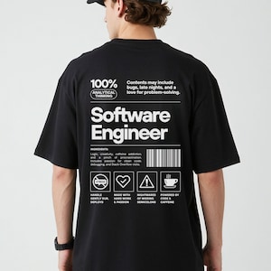 Könnte beinhalten: Schwarzes T-Shirt mit weißem Text "Software Engineer". Das Shirt enthält eine Zutatenliste und Symbole. Der Text "100% Analytical Thinking" wird ebenfalls angezeigt. Ein lässiges Kleidungsstück.