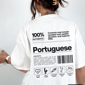 May include: White t-shirt with the word "Portuguese" in large black letters. The shirt includes text that reads "100% Authentic" and "Contents may include saudade soul, pastéis devotion, and explorer DNA." Below are illustrated icons and text.