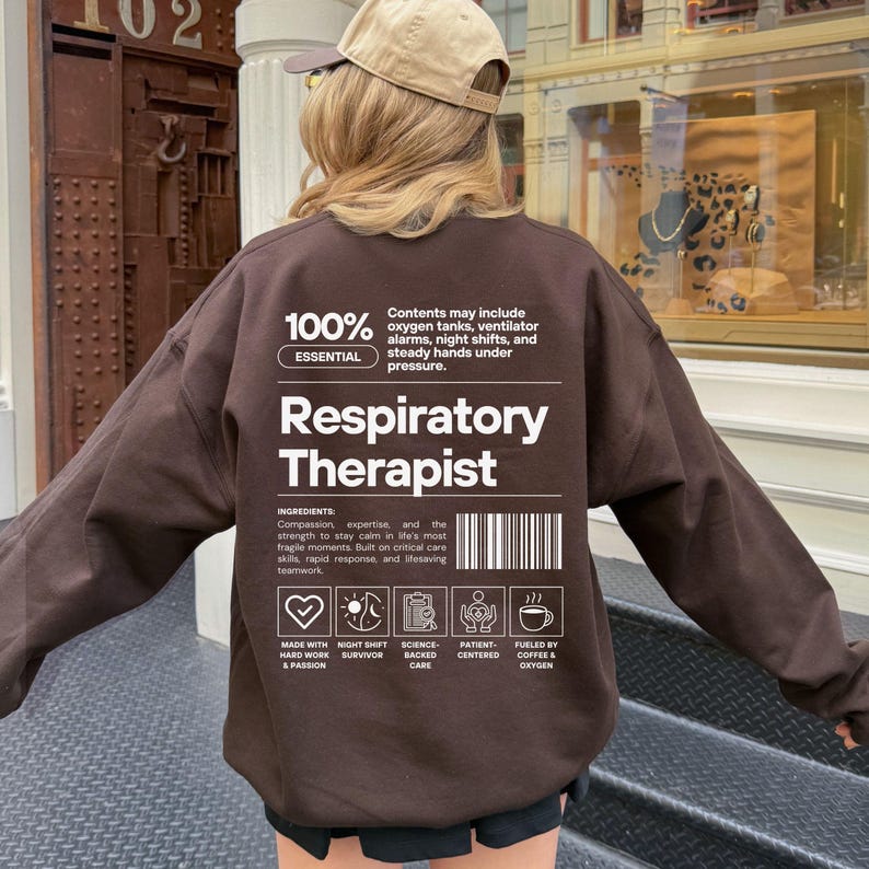 Może przedstawiać: Brązowa bluza z napisem "Respiratory Therapist" w kolorze białym. Bluza zawiera r&oacute;wnież dodatkowy tekst i ikony, w tym "100% Essential" i "Made with Hard Work & Passion."