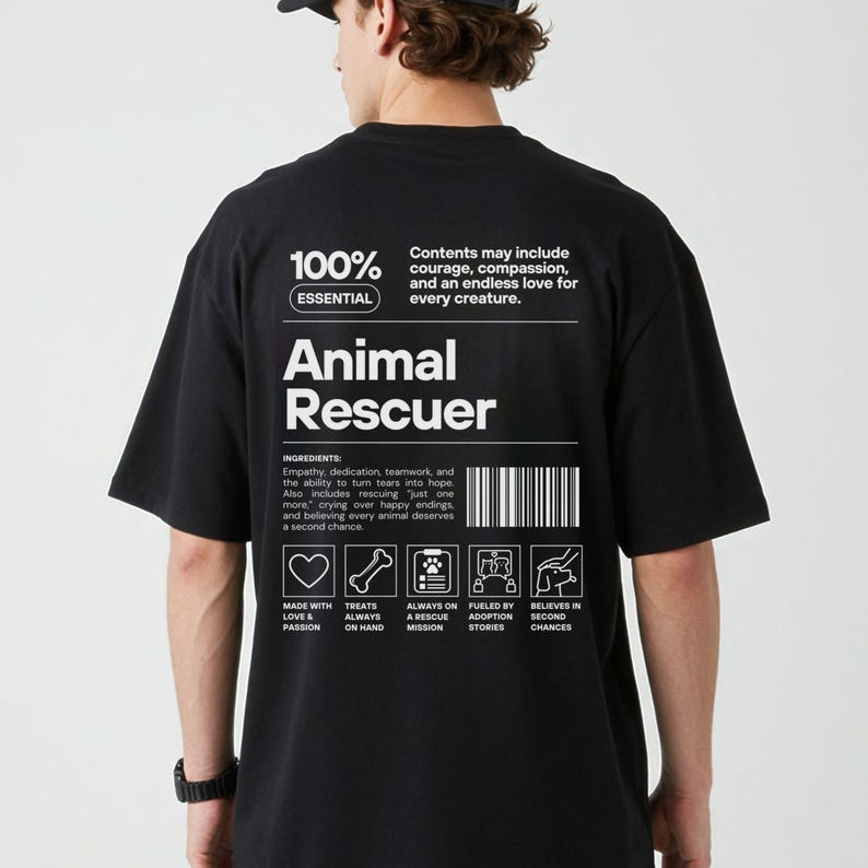 Op de afbeelding: Zwart t-shirt met de witte tekst "Animal Rescuer". Het ontwerp bevat "100% Essential" en een ingredi&euml;ntenlijst. De achterkant van het shirt heeft iconen en tekst over dierenredding.