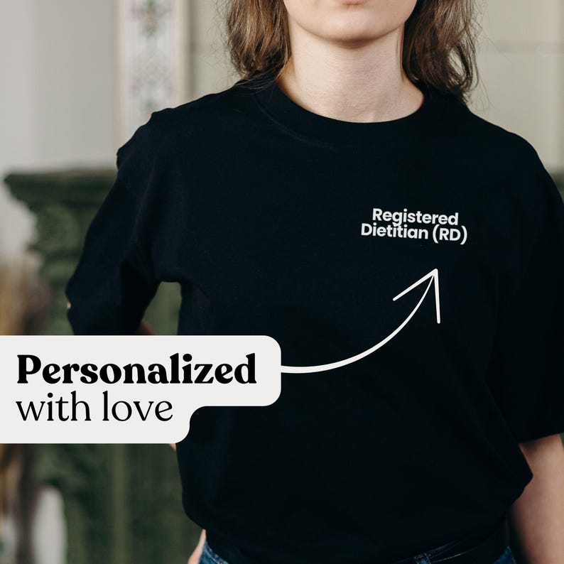 Pu&ograve; includere: T-shirt nero girocollo con la scritta "Registered Dietitian (RD)" e una freccia verso l'alto. La frase "Personalizzato con amore" &egrave; visualizzata in un fumetto bianco.