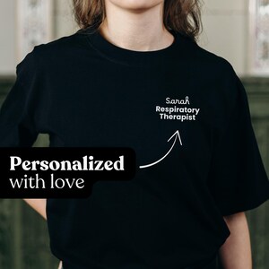 Może przedstawiać: Czarny t-shirt z okrągłym dekoltem z napisem "Sarah Respiratory Therapist" i strzałką wskazującą na tekst. Fraza "Personalized with love" znajduje się w czarnym prostokącie po lewej stronie u dołu.