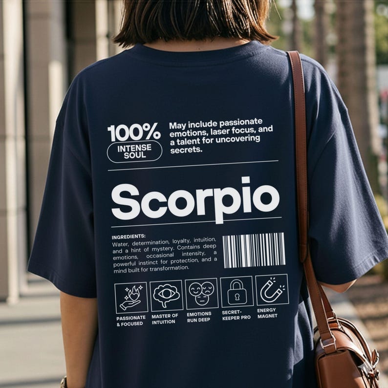 Pode incluir: Camiseta azul marinho com a palavra "Scorpio" em branco. A camiseta apresenta texto que descreve os tra&ccedil;os de Escorpi&atilde;o, como "Alma Intensa" e "Apaixonado e Focado". A parte de tr&aacute;s da camiseta inclui um design de c&oacute;digo de barras e &iacute;cones.