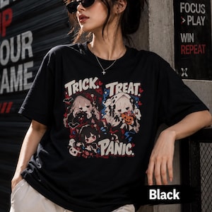 以下が含まれることがあります： 黒の半袖Tシャツで、アニメスタイルのキャラクター3人と「TRICK. TREAT. PANIC.」という文字がプリントされています。デザインには、赤、白、青のコウモリ、幽霊、カボチャ、キャンディといったハロウィーンの要素が含まれています。