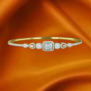 May include: A gold bracelet with a series of diamonds. The bracelet features a square-cut diamond surrounded by smaller diamonds, and other diamond shapes. The bracelet is set against an orange background.
