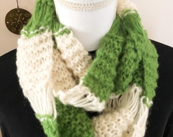 Könnte beinhalten: Ein grob gestrickter Infinity-Schal mit abwechselnden breiten horizontalen Streifen aus grasgrünem und cremeweißem Garn. Der Schal hat ein lockeres, strukturiertes Gewebe mit sichtbaren Maschen und einem weichen, flauschigen Aussehen, drapiert um einen weißen Hals.