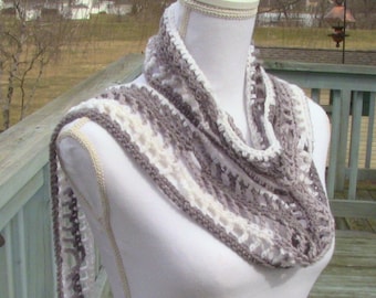 Könnte beinhalten: Handgefertigter Crochet-Loop-Schal in Grau- und Cremetönen, präsentiert auf einer weißen Schaufensterpuppe. Der Schal hat ein sich wiederholendes Lochmuster und ist um den Hals und die Schultern der Schaufensterpuppe drapiert. Ein gemütliches Accessoire.