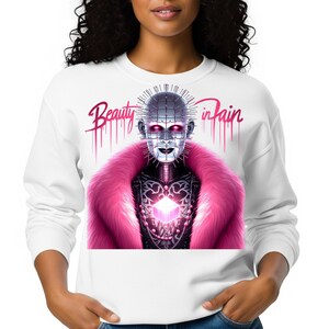 May include: White sweatshirt featuring a graphic of a character with a metallic face, pink fur collar, and the text "Beauty in Pain". The design includes a glowing cube and dripping pink accents.