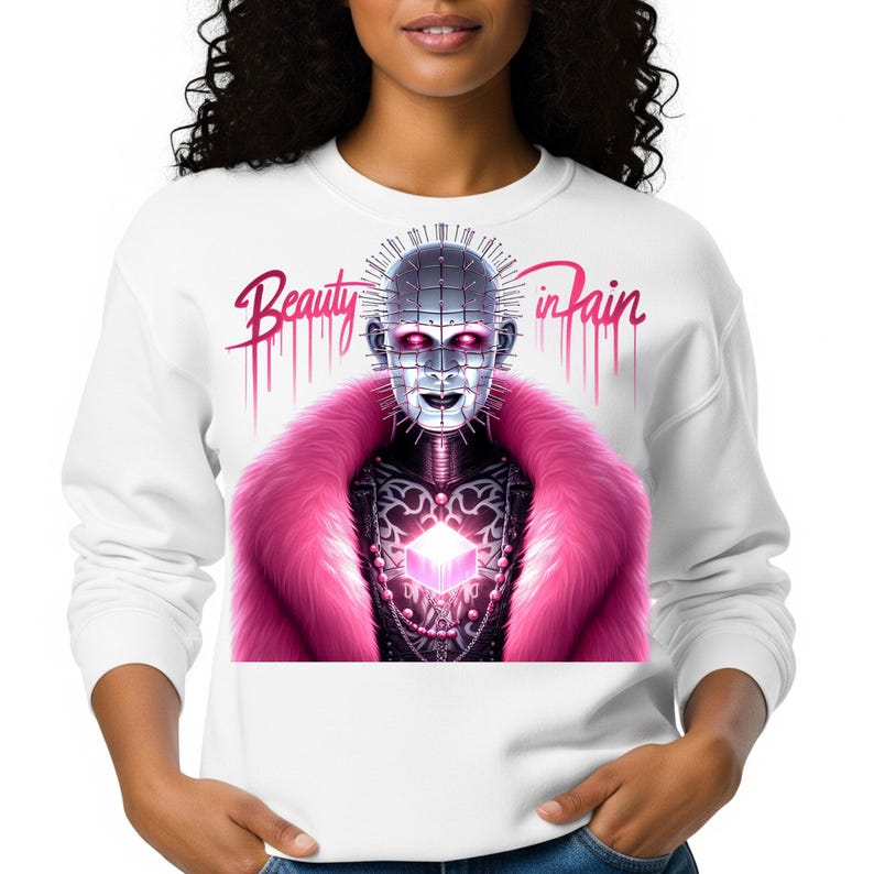 May include: White sweatshirt featuring a graphic of a character with a metallic face, pink fur collar, and the text "Beauty in Pain". The design includes a glowing cube and dripping pink accents.