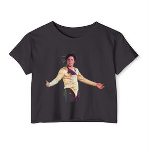 May include: Black crop top t-shirt featuring a graphic of Michael Jackson in a gold jacket and black pants. The image shows Jackson with his arms outstretched. The shirt is made of a soft, comfortable material.