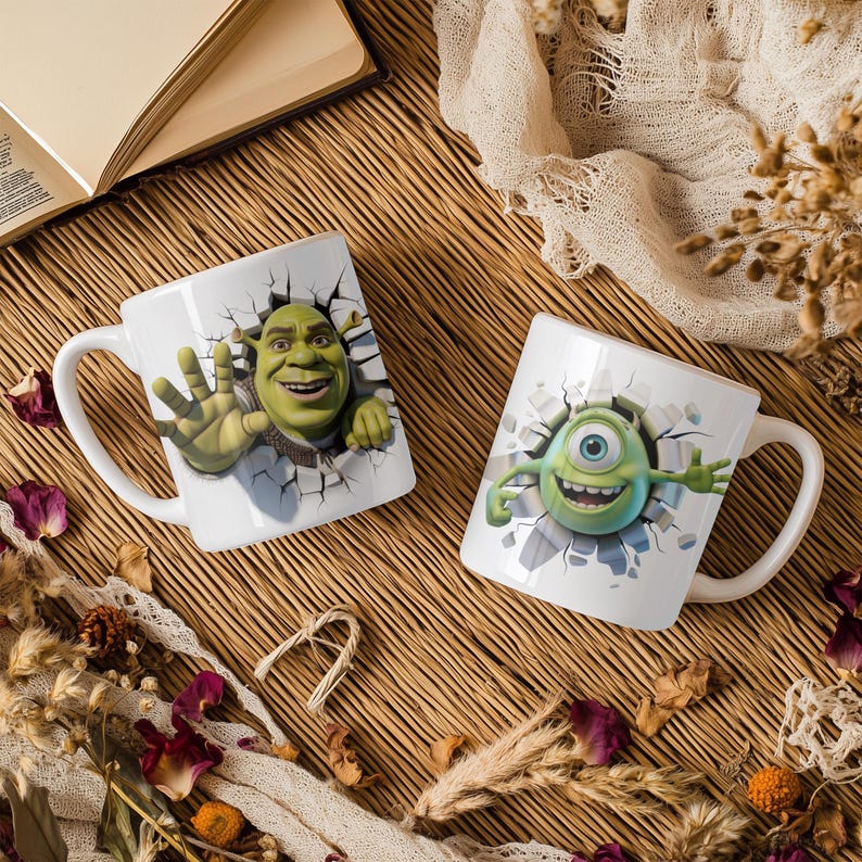 May include: Two white ceramic mugs with cartoon character designs. One mug features Shrek, the other features Mike Wazowski from Monsters, Inc. Both designs appear to be breaking through a wall. The mugs have white handles.