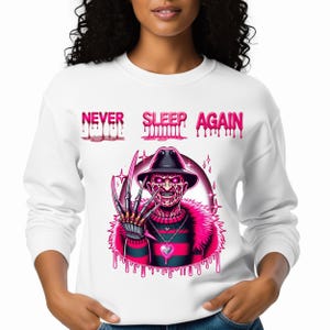 May include: White sweatshirt with a graphic of Freddy Krueger in a hat and claws, with the text "NEVER SLEEP AGAIN" in pink dripping letters. The design features a pink and black striped sweater and a pink fur collar.