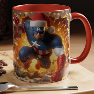 Peut inclure: Une tasse &agrave; caf&eacute; avec une poign&eacute;e rouge repr&eacute;sentant Captain America portant un bonnet de P&egrave;re No&euml;l. Le design de la tasse comprend un fond festif et un int&eacute;rieur rouge. La tasse est sur une surface en bois.