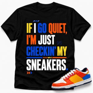 May include: Black t-shirt with the text "IF I GO QUIET, I'M JUST CHECKIN' MY SNEAKERS" in white, orange, blue, and yellow. A colorful sneaker with red, orange, yellow, blue, and white accents is visible on the bottom right.