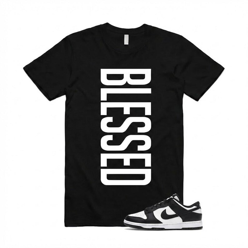 Pu&ograve; includere: T-shirt nero con la scritta "BLESSED" in grandi lettere maiuscole bianche. Un paio di scarpe da ginnastica bianche e nere &egrave; posizionato nella parte inferiore della maglietta. Le scarpe da ginnastica hanno una suola bianca e un logo Nike nero.
