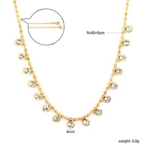 Pode incluir: Colar dourado com uma delicada corrente de pequenas contas e pedras preciosas redondas e transparentes. O colar tem aproximadamente 40 cm de comprimento, com uma corrente ajust&aacute;vel adicional de 5 cm. As pedras preciosas t&ecirc;m 4 mm de di&acirc;metro.