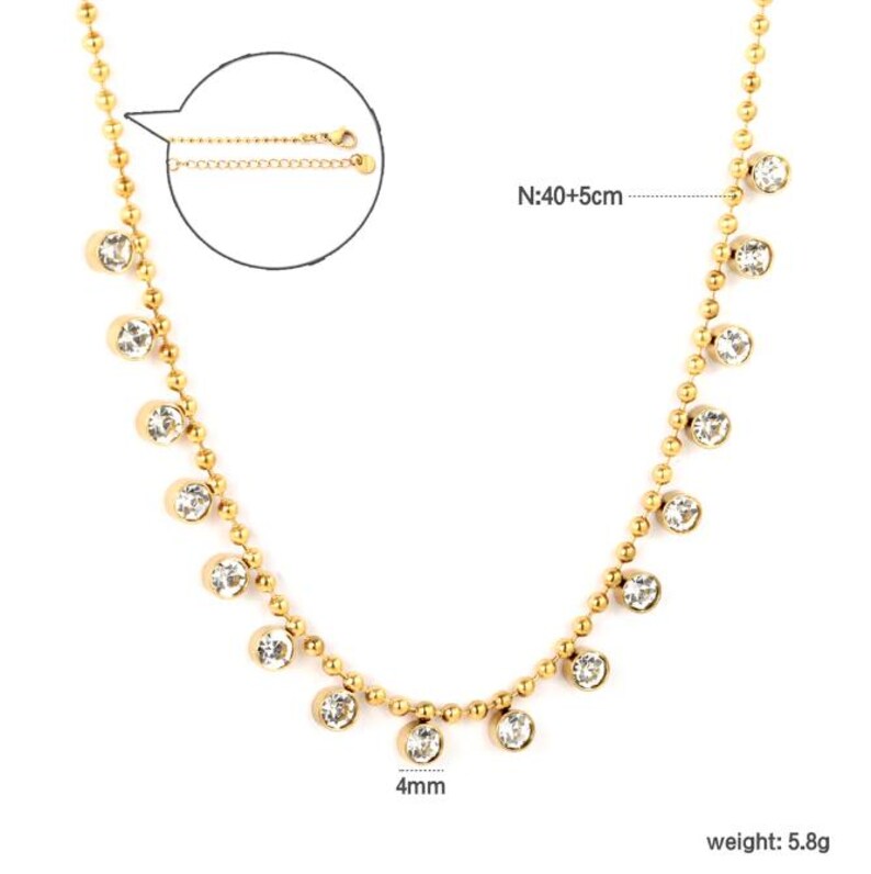 Pode incluir: Colar dourado com uma delicada corrente de pequenas contas e pedras preciosas redondas e transparentes. O colar tem aproximadamente 40 cm de comprimento, com uma corrente ajust&aacute;vel adicional de 5 cm. As pedras preciosas t&ecirc;m 4 mm de di&acirc;metro.