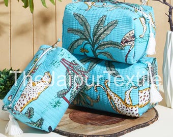 Pode incluir: Três nécessaires azul claro com textura acolchoada, com uma estampa com tema de selva de leopardos e palmeiras. Cada bolsa tem um puxador de zíper com borla branca. As bolsas são empilhadas em uma superfície de madeira.