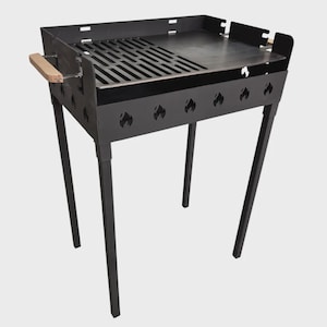 Könnte beinhalten: Ein schwarzer Metallgrill mit flacher Oberseite und Rost. Der Grill hat einen Holzgriff und flammenförmige Aussparungen an den Seiten. Er steht auf vier abgewinkelten Beinen.