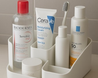 May include: A white plastic organizer filled with skincare products. Includes a bottle of Bioderma Sensibio H2O, CeraVe Moisturizing Cream, a toothbrush, and La Roche-Posay Anthelios 50+ sunscreen. Also includes a jar of Laneige cream.