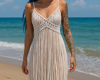 May include: A floor-length, off-white macramé dress featuring thin spaghetti straps, a V-neckline, and a bodice constructed with intricate knotted cord patterns that transition into long, vertical fringe strands extending to the hem.