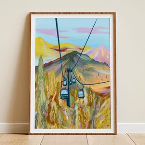 以下が含まれることがあります： スキーリフトのある山岳風景のアートプリント。青、黄、ピンクの鮮やかな色彩が特徴です。スキーリフトのゴンドラは青色で、木製のフレームに額装されています。