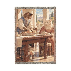 May include: A woven throw blanket featuring a detailed scene of three cats in human-like clothing gathered around a wooden dining table. One cat stands serving food, another sits at the table, and a small kitten peeks from underneath.