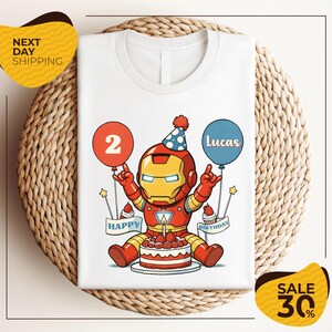 A white t-shirt with a cartoon image of a child wearing a party hat and holding balloons, celebrating a birthday.