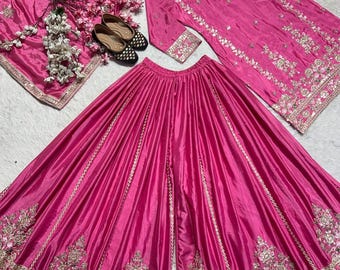 Può includere: Un vivace completo etnico indiano color fucsia. Il set comprende una tunica a maniche lunghe, pantaloni a gamba larga e una sciarpa abbinata, tutti adornati da intricati ricami dorati. Un paio di ballerine nere e dorate e accenti floreali completano la presentazione.