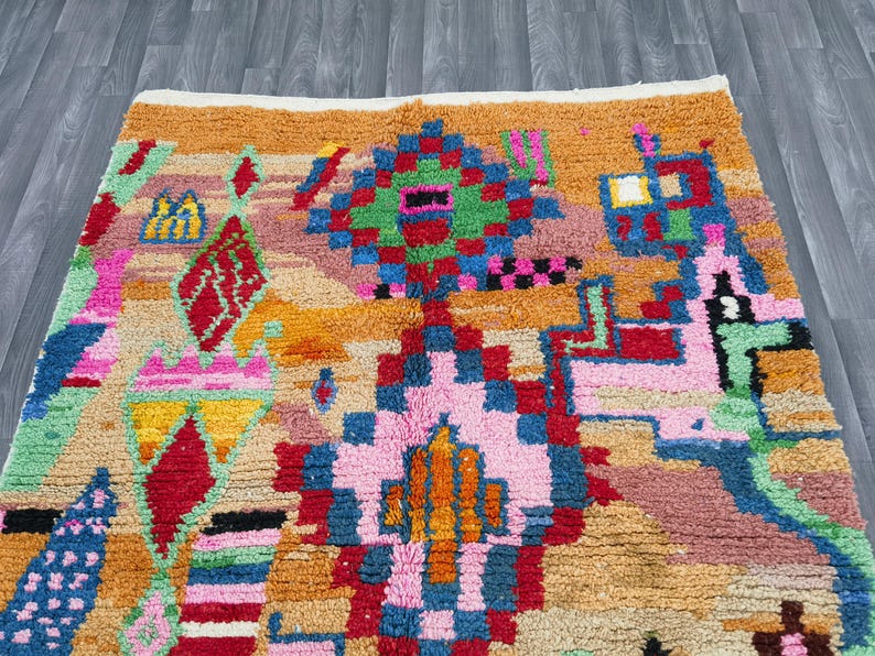 May include: A colorful, patterned rug with a geometric design. The rug features a variety of colors, including orange, pink, green, blue, and red. The design includes diamond and square shapes.