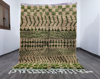 Könnte beinhalten: Ein beigefarbener und grüner Teppich mit geometrischem Muster. Der Teppich hat ein sich wiederholendes Muster aus grünen Formen auf beigem Hintergrund. Der Teppich hat einen Fransenbesatz am unteren Rand. Der Teppich besteht aus dickem, gewebtem Material.