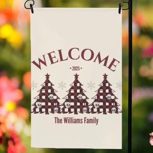 Könnte beinhalten: Eine cremefarbene Gartenflagge mit dem Wort "WELCOME" oben, dem Jahr "2025" darunter und dem Familiennamen unten. Drei Weihnachtsbäume mit einem rot-schwarzen Karomuster und Totenkopfakzenten befinden sich in der Mitte.